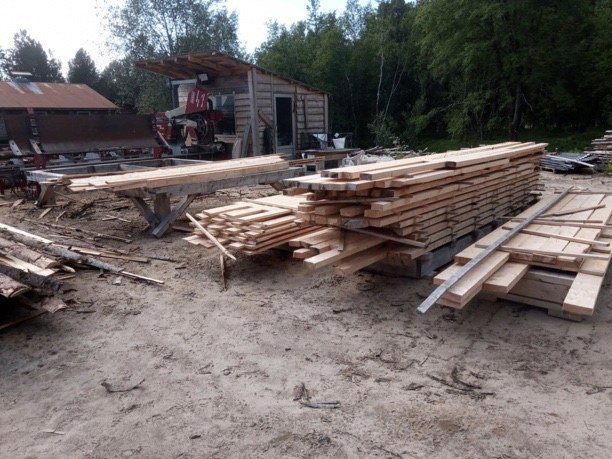 Stabler med nysagede bord og planker på sagtomta